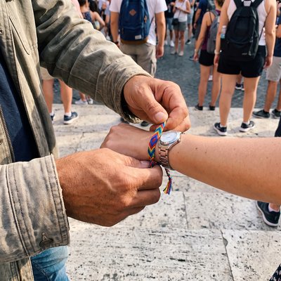 A stranger tying a string bracelet onto a tourist wrist on the Spanish Steps